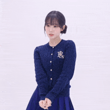 a woman wearing a blue cardigan with the letter r on the front