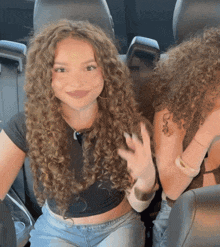 a girl with curly hair has a tattoo on her arm that says love