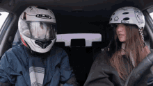 a man wearing a hjc helmet sits next to a girl wearing a globe helmet