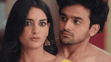 a man without a shirt is standing next to a woman with earrings