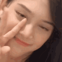 a close up of a woman holding her finger to her nose .