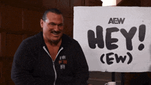 a man sits in front of a sign that says hey ( ew )