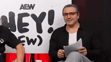 a man sitting in front of a sign that says aew