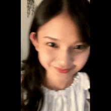 a close up of a woman 's face with a white shirt on
