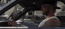 a man wearing sunglasses and a baseball cap is driving a car