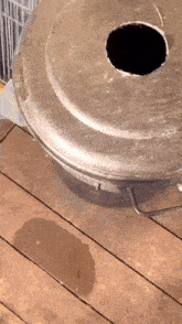 a dirty trash can with a hole in the lid is on a wooden floor .