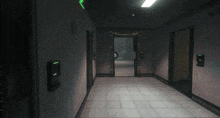 a dark hallway with a green exit sign on the right