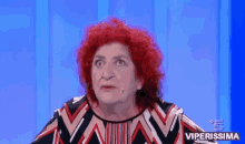 a woman with red hair is making a funny face in front of a blue background with the words viperissima written on it
