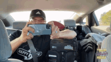 a man is taking a picture in the back seat of a car with a bag that says ' strange ' on it