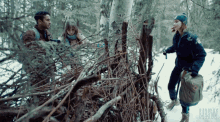 a man and a woman are standing in a snowy forest with the letters uhw on the bottom