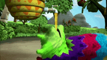 a green and purple cartoon character is drinking from a faucet
