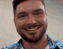 a man with a beard wearing a blue shirt is smiling