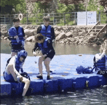 a group of people wearing life jackets are standing on a raft in the water .