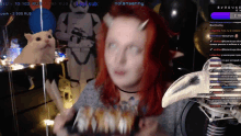 a woman with red hair and horns is on a stream with a cat and a storm trooper