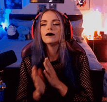 a woman with blue hair is wearing headphones and making a funny face