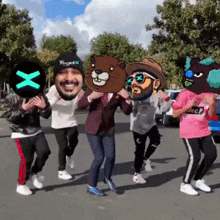 a group of people are dancing in a parking lot and one of them has a x on his hat