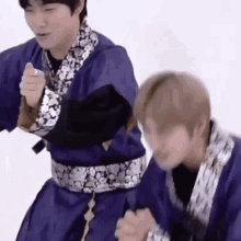 two men are standing next to each other in purple kimonos .