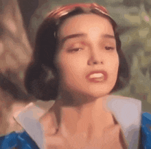 a close up of a woman 's face wearing a blue dress and a red headband .