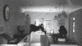 a black and white photo of a kitchen with a clock on the wall above the sink