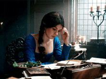 a woman in a blue dress is reading a book