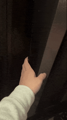 a person 's hand is reaching out towards a dark wall