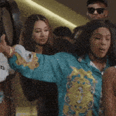 a woman in a blue shirt has her arms outstretched in a crowd of people