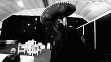 a man wearing a sombrero is standing in a dark room .