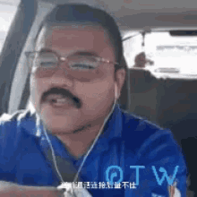 a man with a mustache and glasses is wearing a blue shirt and headphones .