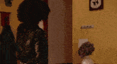 a woman in a leather jacket stands in front of a wall with a picture of two cats on it