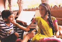 a little girl in a yellow sari is being interviewed