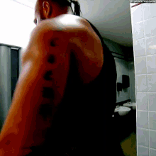 a man in a black tank top has a tattoo on his arm that says ' the next big thing '
