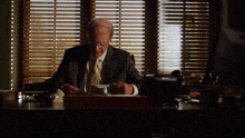 a man in a suit and tie sits at a desk