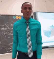 a man in a green shirt and tie is standing in front of a blackboard that says ' a ' on it