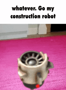 a robot is sitting on a pink rug in a room and says `` whatever . go my construction robot '' .