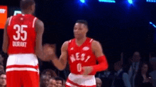 a couple of basketball players are shaking hands on a court .