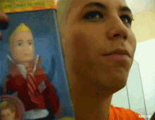 a woman in an orange shirt is holding a picture of a doll