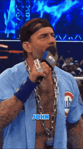 a man with a chain around his neck is holding a microphone with the name john written on it