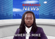 a man is sitting in front of a breaking news screen