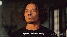 a man with curly hair says spend frivolously in front of a sign for ironheart