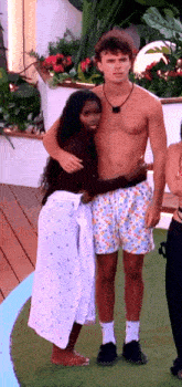 a man without a shirt is hugging a woman in a white skirt