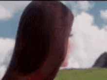 a woman with long red hair is standing in a field .