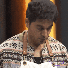 a man wearing an apron and a sweater with a pattern of snowflakes on it