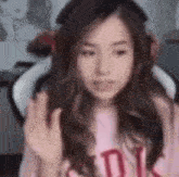 a woman wearing headphones and a pink shirt is giving a middle finger .