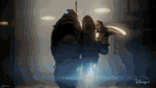 a couple of people standing next to each other in a dark room with a disney logo in the background
