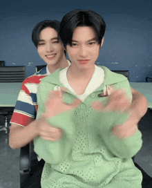 a man in a green sweater is hugging another man in a red and white striped shirt