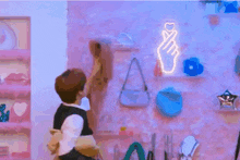 a man is holding a woman in his arms in front of a pink wall with a neon sign that says i love you .