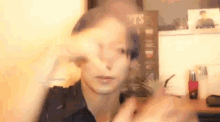 a man is making a funny face with his hands while sitting at a desk .