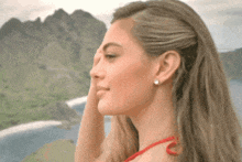a woman covering her face with her hand in front of mountains