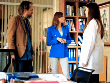 a woman in a blue jacket is talking to two men