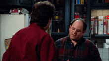 two men are talking in a kitchen with a box of kellogg 's cereal on the shelf